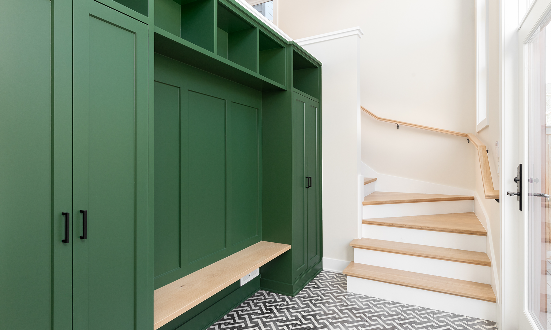 Mud room with painted custom built in wall cabinets and bench painted green with patterned tile