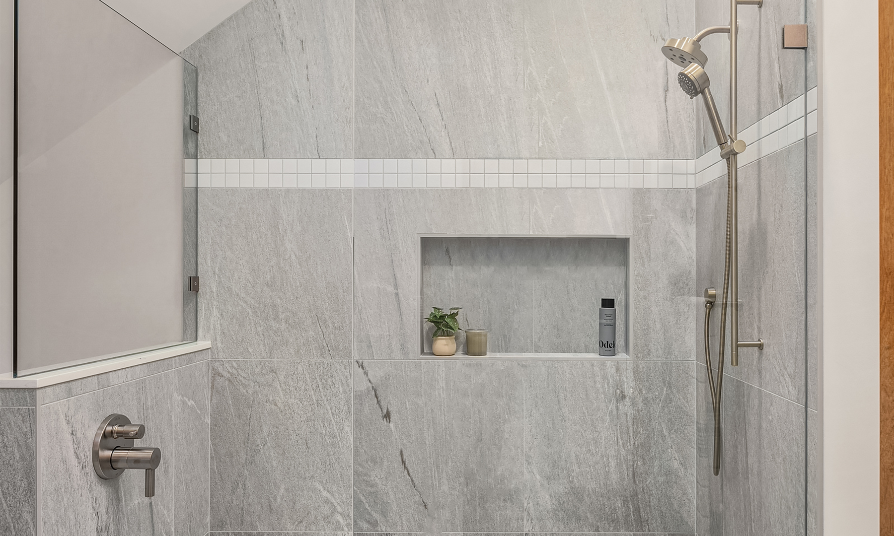 Spacious modern shower with hand shower and controls on opposite wall